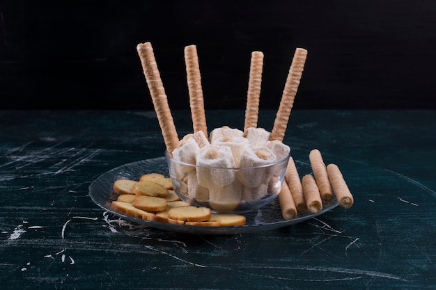 Galletas y palitos de gofres con lokum turco en bandeja de vidrio