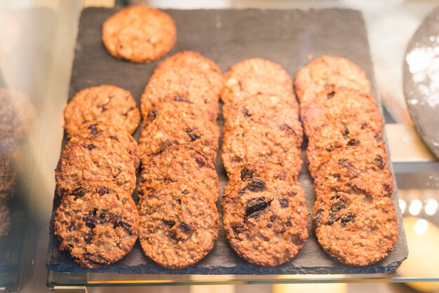 Galletas de pasas de avena recién horneadas en bandeja en el gabinete de vidrio