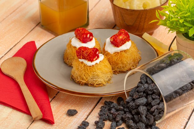 Galletas de pastelería oriental dentro de la placa con crema blanca piña seca y frutos secos sobre la mesa de madera