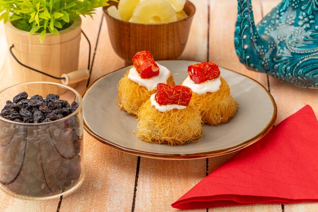 Galletas de pastelería oriental dentro del plato con crema blanca junto con anillos de piña secos frutos secos