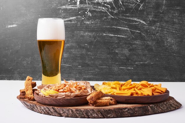 Galletas y patatas fritas con un vaso de cerveza en blanco.