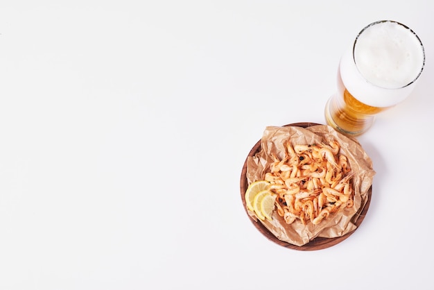 Galletas y patatas fritas con un vaso de cerveza en blanco.