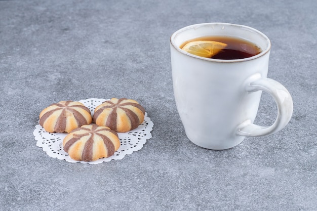 Galletas de patrón de cebra y taza de té en la superficie de mármol