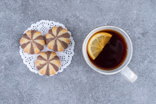 Galletas de patrón de cebra y taza de té en la superficie de mármol
