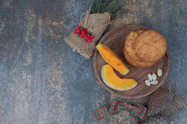 Galletas con piñas y dos rodajas de calabaza en plato de madera.