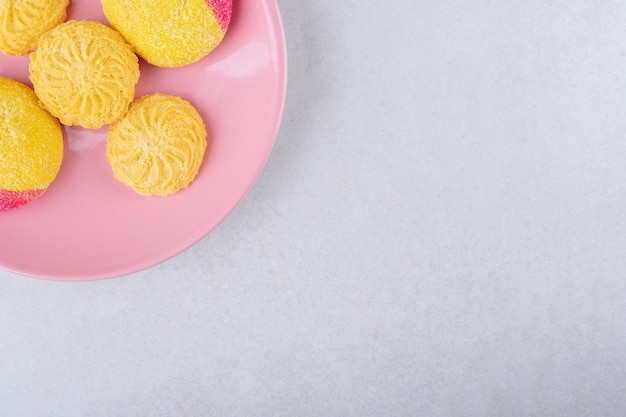 Galletas en una placa rosa sobre mesa de mármol.