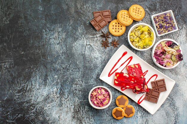 Galletas y un plato de chocolate con cuencos de flores secas a la derecha sie de gris