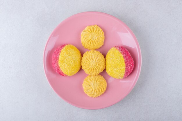 Galletas en un plato rosa, en el mármol.