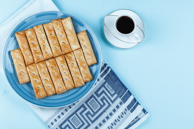 Galletas en un plato y una taza de café sobre fondo azul.