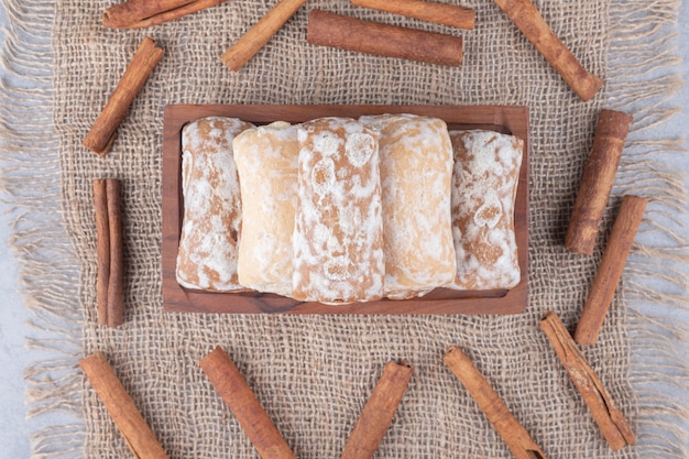 Foto gratuita galletas pryanik rusas en una pequeña bandeja, rodeadas de ramas de canela en mesa textil.