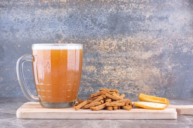 Galletas, queso y vaso de cerveza sobre tabla de madera. Foto de alta calidad