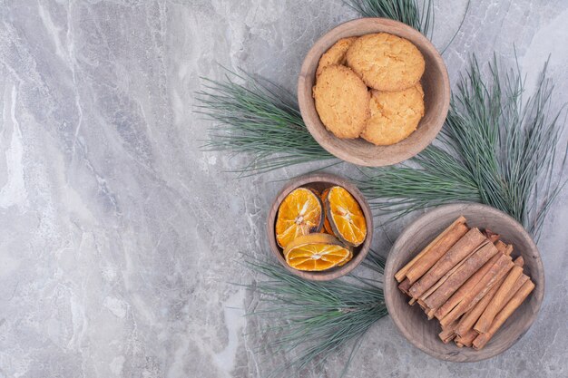 Galletas, ramas de canela y rodajas de naranja en vasos de madera