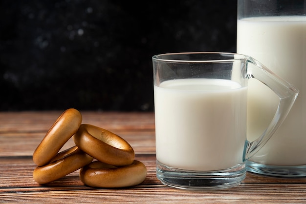 Galletas redondas, una botella de leche y un vaso de leche en la mesa de madera.