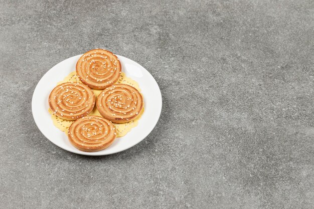 Galletas redondas con semillas de sésamo en la placa blanca.