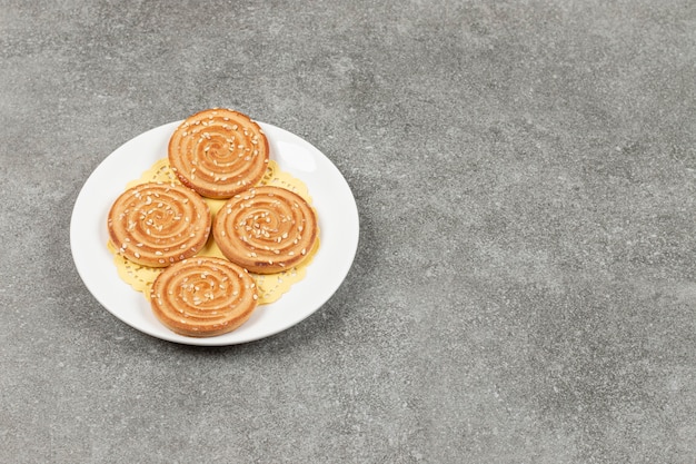 Galletas redondas con semillas de sésamo en la placa blanca.