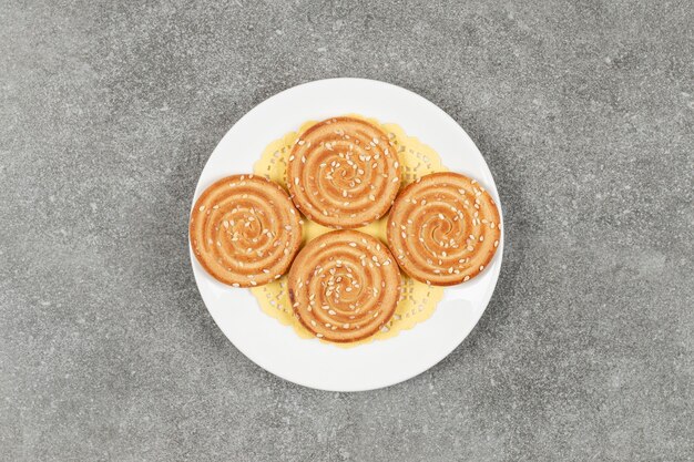 Galletas redondas con semillas de sésamo en la placa blanca.