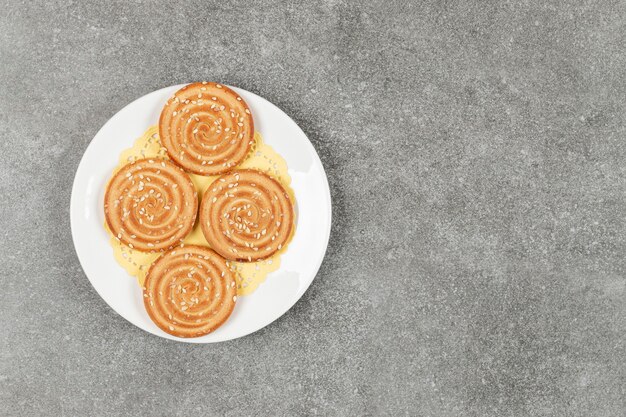 Galletas redondas con semillas de sésamo en la placa blanca.