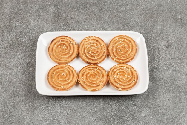 Galletas redondas con semillas de sésamo en placa cuadrada blanca