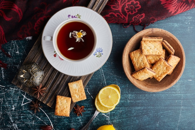 Galletas con relleno de cacao en una taza de madera con una taza de té, vista superior.