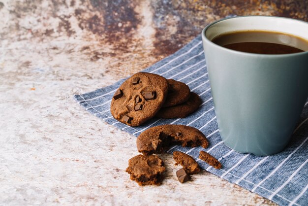 Galletas rotas con taza de café sobre fondo rústico