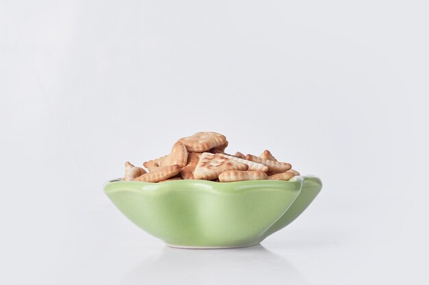 Galletas saladas en un plato de cerámica verde sobre gris