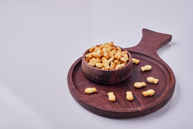 Galletas saladas en una taza de madera aislada sobre fondo gris