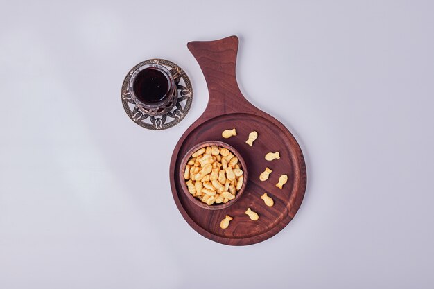 Galletas saladas en una taza de madera con un vaso de té, vista superior.