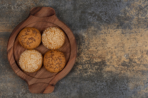 Galletas con semillas de sésamo y trozos de chocolate sobre tabla de madera.