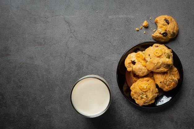 Galletas servidas con un vaso de leche en piso oscuro