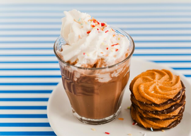 Galletas y taza de café espresso con chocolate y crema batida