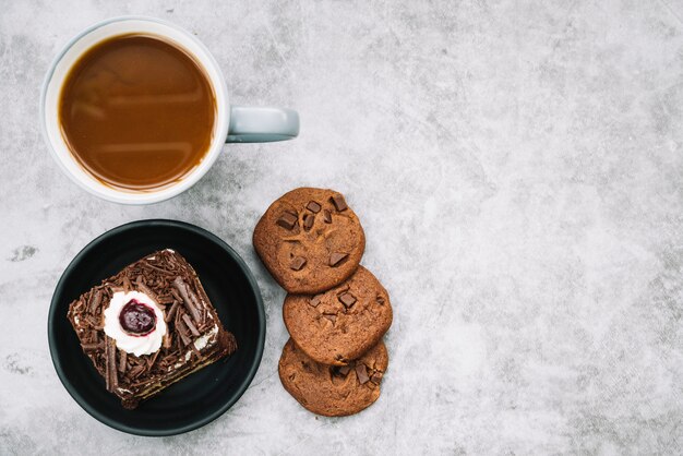 Galletas; taza de café y rebanada de pastel en el fondo