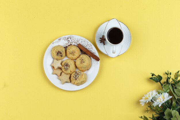 Galletas y taza de café sobre un fondo amarillo