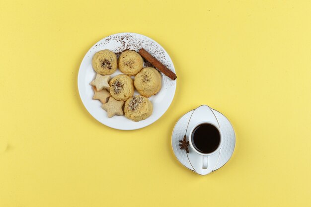 Galletas y taza de café sobre un fondo amarillo