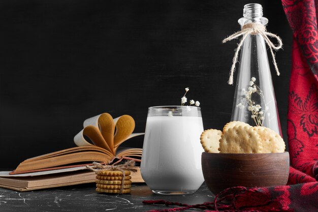 Galletas en una taza de madera con un vaso de leche.