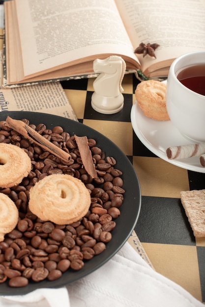 Galletas y una taza de té en un tablero de ajedrez
