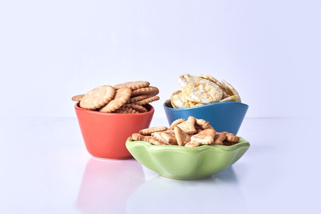 Galletas en tazas de colores sobre blanco.