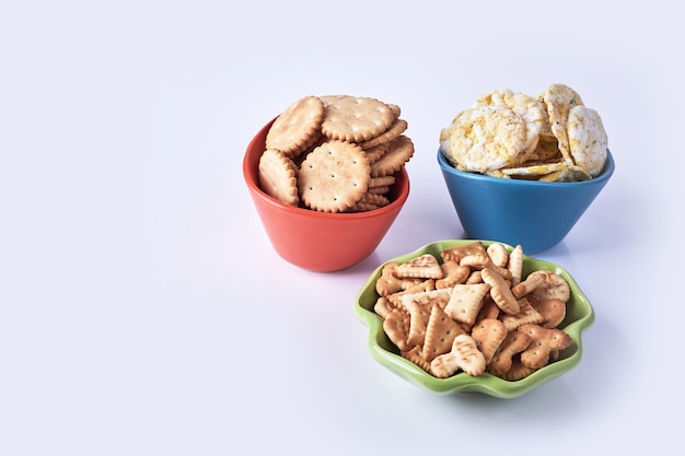 Galletas en tazas de colores sobre blanco.