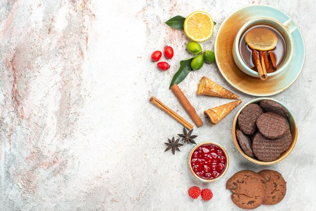 galletas tazón de mermelada galletas de chocolate una taza de té con palitos de canela y limón