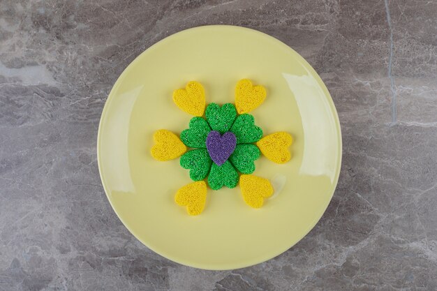 Galletas verdes y amarillas, en el plato, en la superficie de mármol