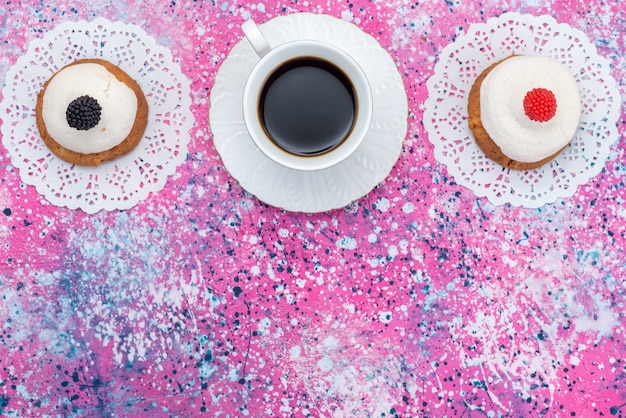 Galletas de vista superior con crema junto con una taza de café en la masa dulce de azúcar de pastel de escritorio color