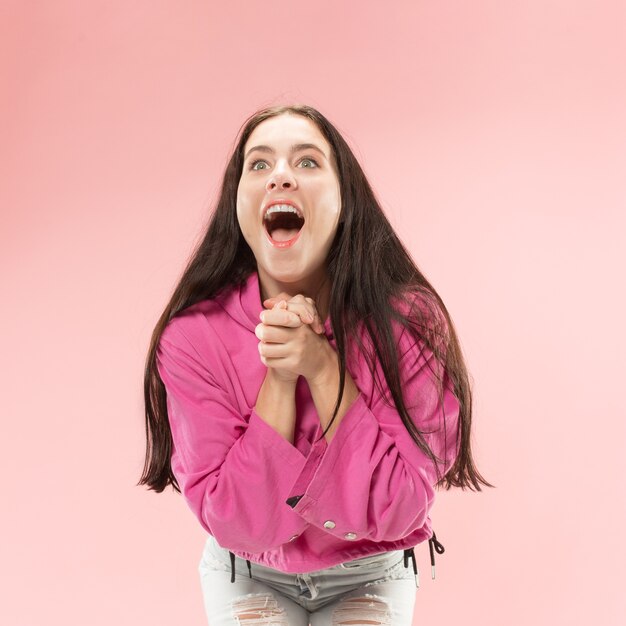 Ganar éxito mujer feliz celebrando ser un ganador. Imagen dinámica del modelo de mujer caucásica sobre fondo rosa de estudio.