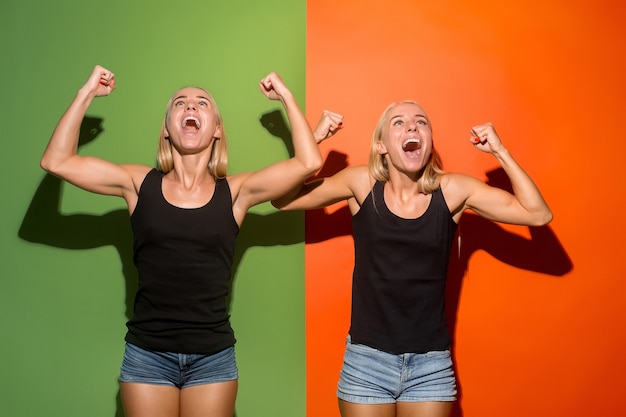 Gané. Ganar éxito mujeres felices celebrando ser un ganador. Imagen dinámica de modelos femeninos caucásicos sobre fondo de estudio. Victoria, concepto de deleite. Concepto de emociones faciales humanas. Colores de moda