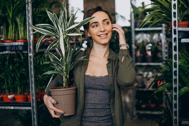 Gardner hembra en casa de plantas con plantas y flores.