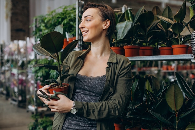 Foto gratuita gardner hembra en casa de plantas con plantas y flores.