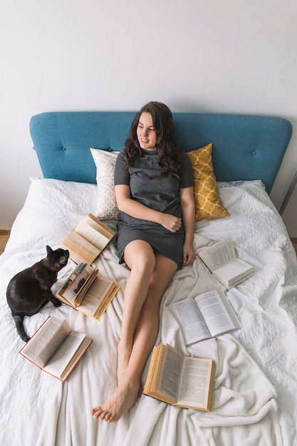 Foto gratuita gato y libros cerca de mujer en la cama