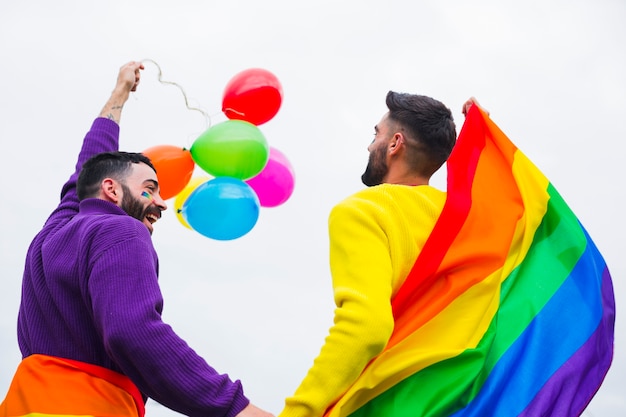 Foto gratuita gays con bandera arcoiris y globos disfrutando de desfile.