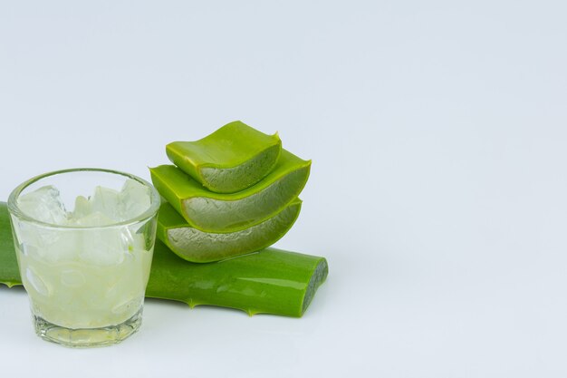 La gelatina de aloe vera en un vaso con licencia de aloe vera está cerca de la pared blanca.