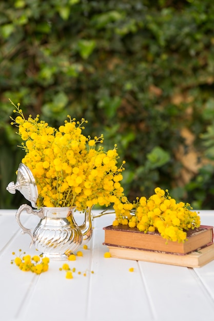 Genial escena con flores amarillas, tetera y libros