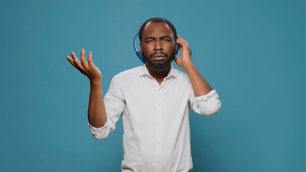 Genial hombre feliz escuchando música estéreo en auriculares de audio, usando canciones de radio mp3 para divertirse en el estudio. Funky persona alegre disfrutando de un sonido enérgico en los auriculares, sintiéndose alegre.