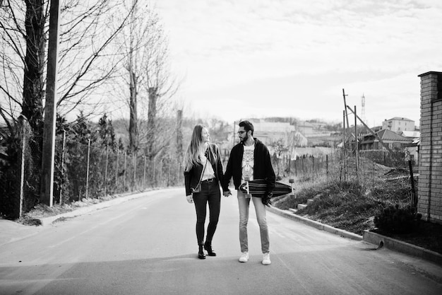 Genial pareja multirracial caminando junto con longboard